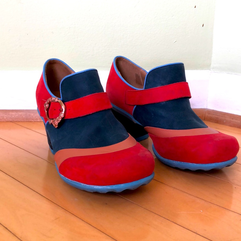 Fleuvog mules in blue, red, and tan with rose gold-colored buckle.